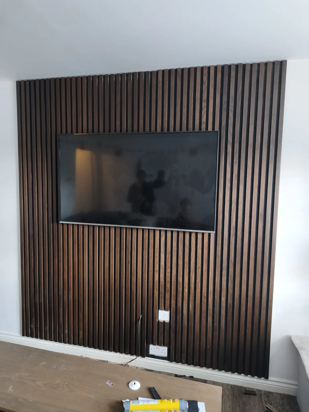 Dark oak slat wall with a wall-mounted TV in a living room