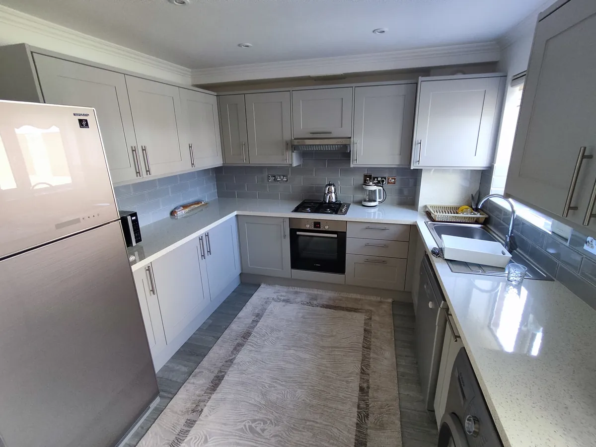 U-shaped fitted kitchen with grey shaker units, a quartz worktop and a built-in oven